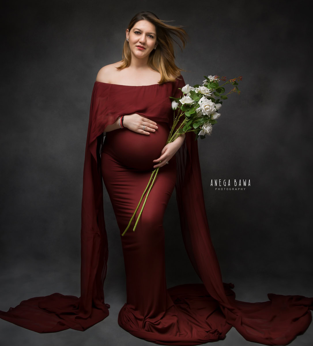 Luxury Maternity Photographer in Delhi: Maroon Gown with Drape and Flowers, Grey Backdrop, by Anega Bawa Photography, Gurgaon Noida.