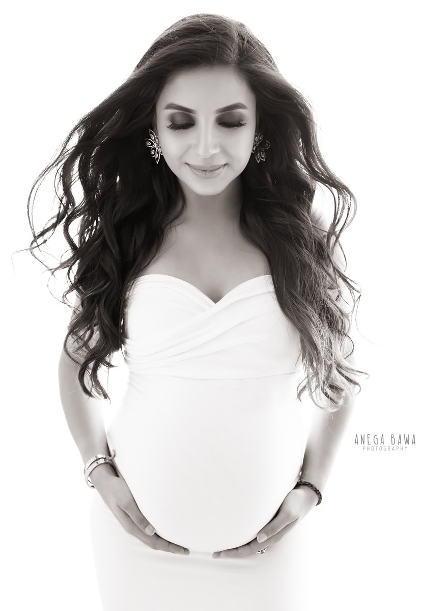 Elegant maternity photography in Delhi featuring a mom-to-be in a beautiful white dress, captured in an all-white theme by Anega Bawa, photographer in Gurgaon and Noida.