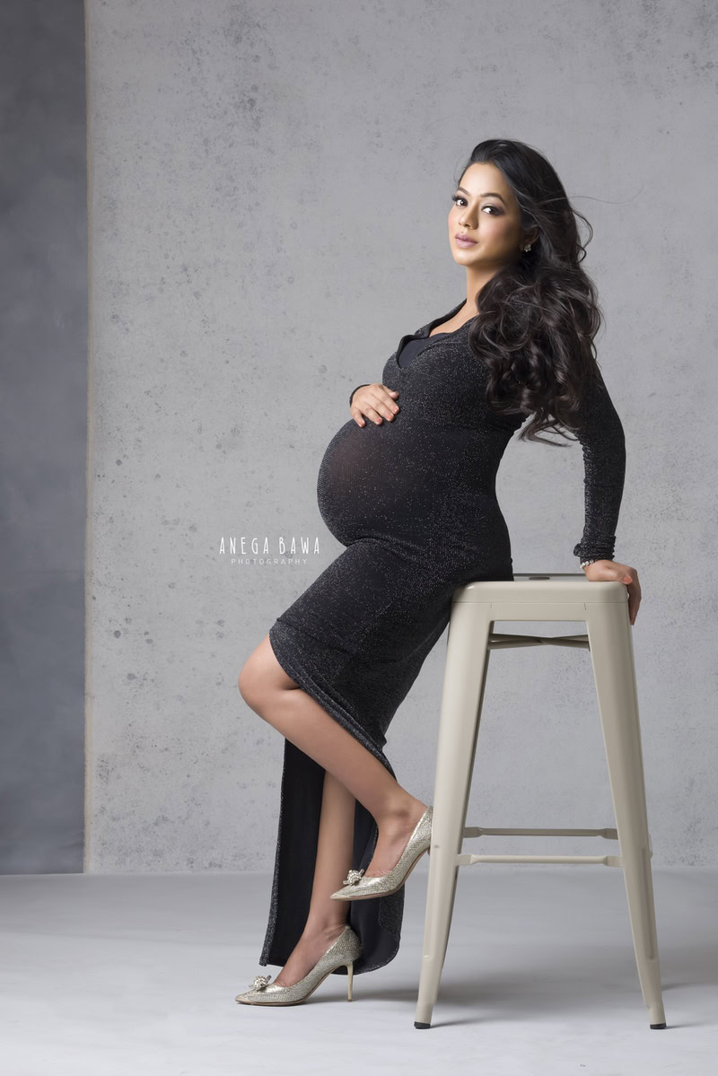 Pregnancy Photography Delhi: Black Slit Dress Sitting, Grey Backdrop by Anega Bawa Photographer, Gurgaon Noida