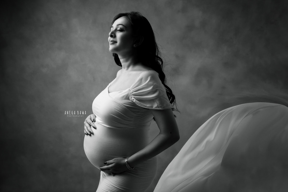 Pregnancy Photography in Delhi: White Dress with Drape, Grey Backdrop, Black and White by Anega Bawa Photography, Gurgaon Noida