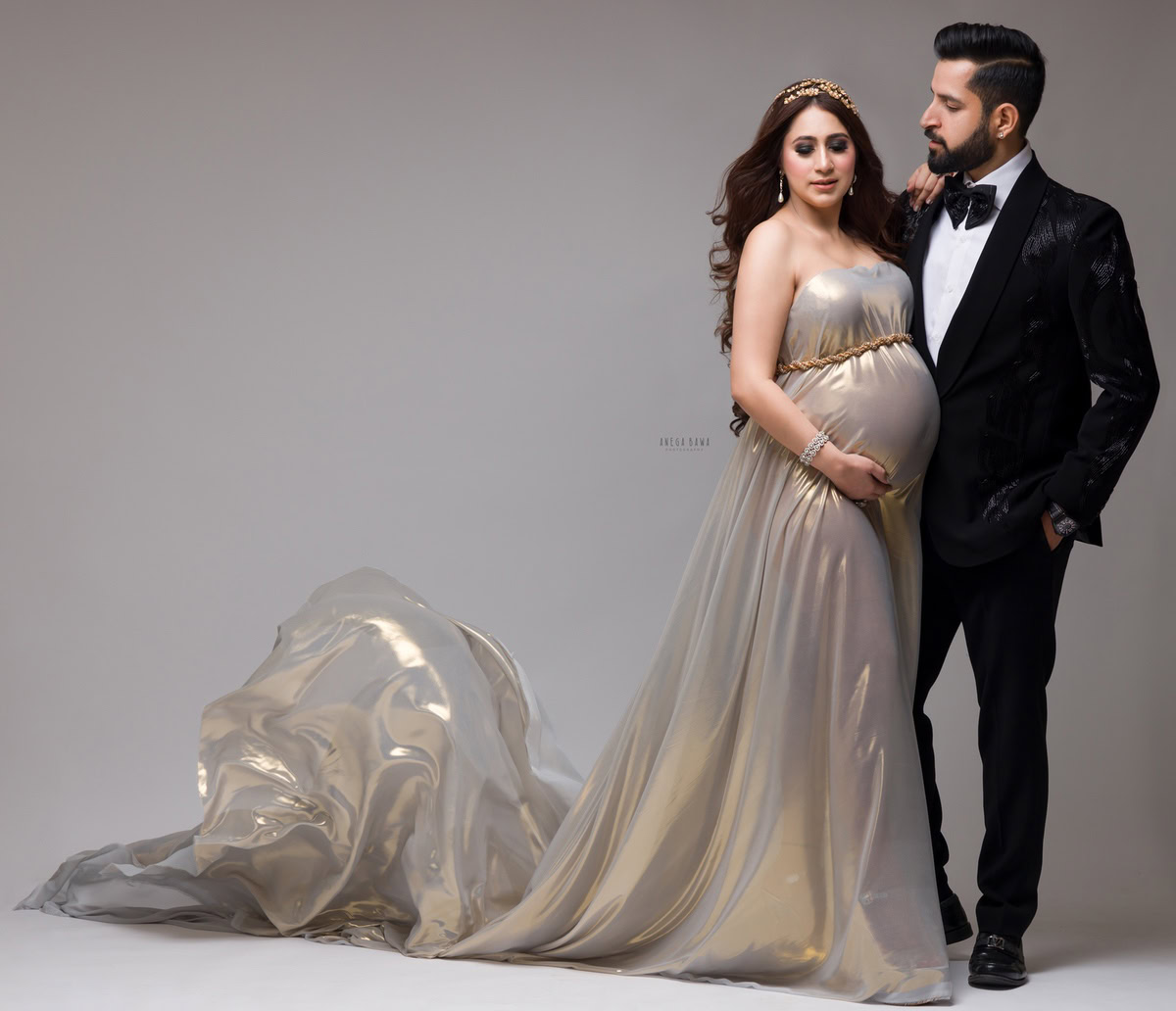 Pregnancy Photoshoot Delhi: Golden Shimmer Wrap with Husband, Grey Backdrop, by Anega Bawa Photography, Gurgaon Noida.