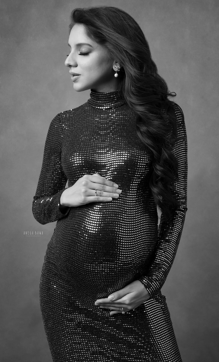 Elegant pregnant woman in shimmering black gown, maternity photography, black and white portrait, professional maternity photoshoot, Anega Bawa Photography.