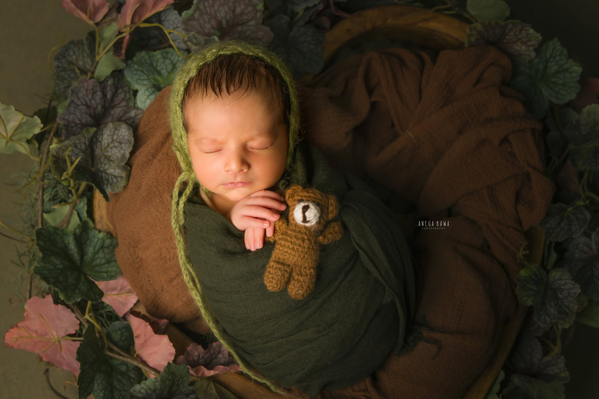 Newborn Photography in Gurgaon: Green Wrap with Soft Toy on Green Backdrop. Photoshoot by Anega Bawa in Delhi Noida.