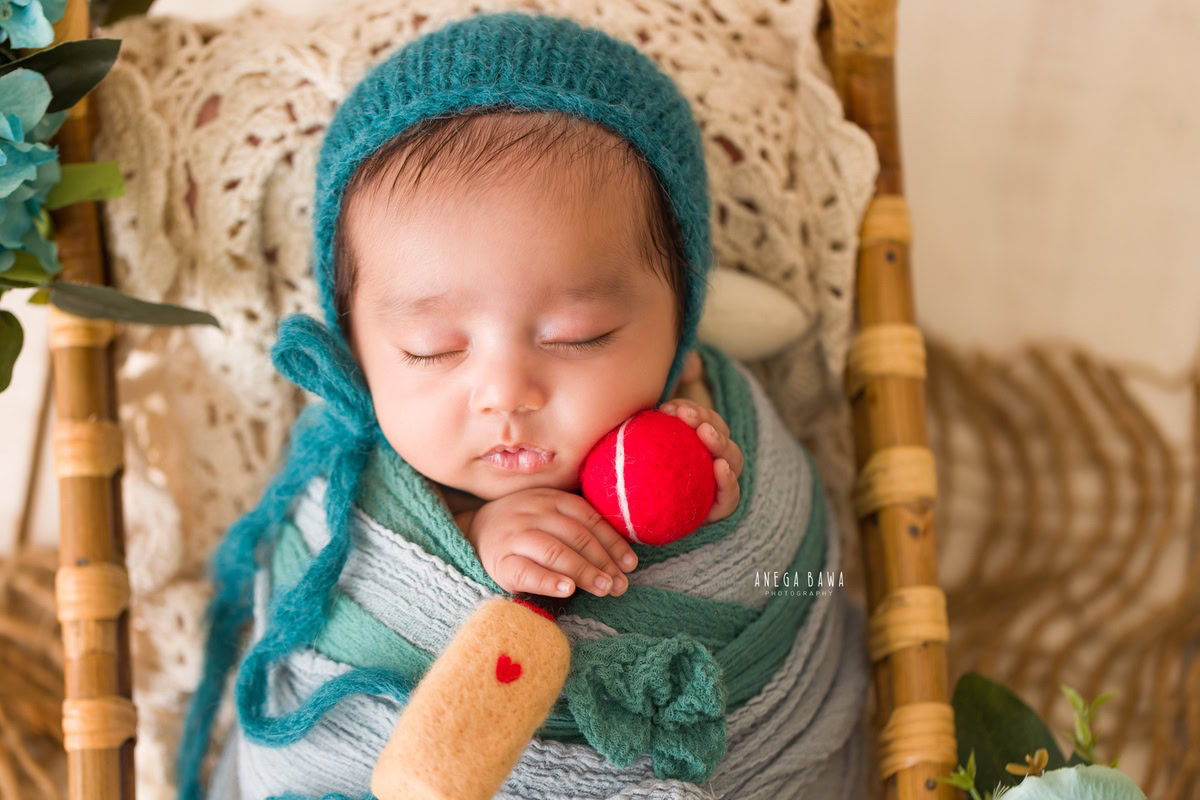 Newborn Photography in Delhi: Blue Wrap with Bat and Ball, White Backdrop, by Anega Bawa Photographer, Gurgaon Noida.