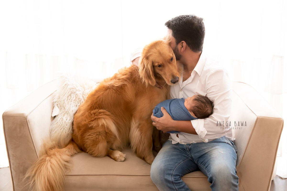 Newborn Photography in Delhi: A baby wrapped in blue with dad and dog on a white backdrop. Photographer: Anega Bawa Photography, Gurgaon.