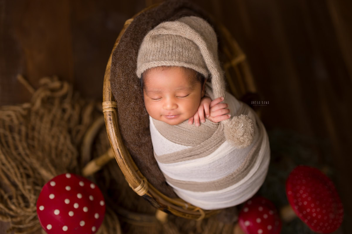 Newborn Photography in Delhi: Brown and White Wrap, Cute Cap, Brown Backdrop. Photographer: Anega Bawa Photoshoot, Gurgaon Noida.