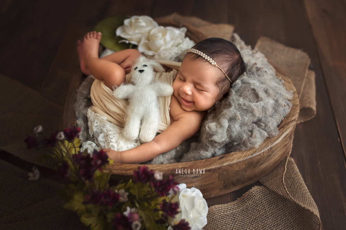 Newborn Photography in Delhi: Beige Wrap with Brown Wooden Basket and Soft Toy on Brown Backdrop. Photographer: Anega Bawa, Gurgaon Noida.