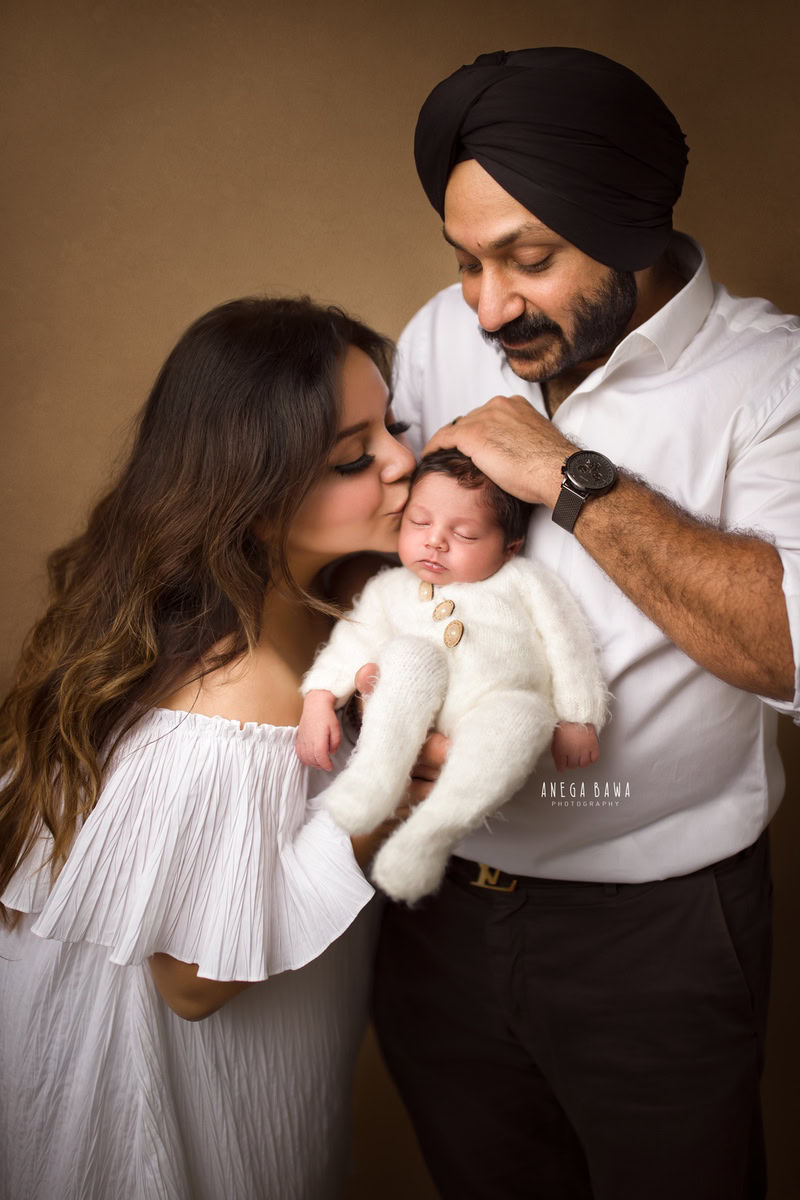 Newborn Photography in Delhi: Family portrait in all white attire against a brown backdrop. Photographer: Anega Bawa Photography, Gurgaon.