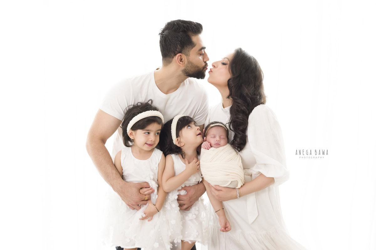 Newborn Photography in Delhi: Family captured in an adorable pose, all dressed in white. Photographer: Anega Bawa Photography, Gurgaon.