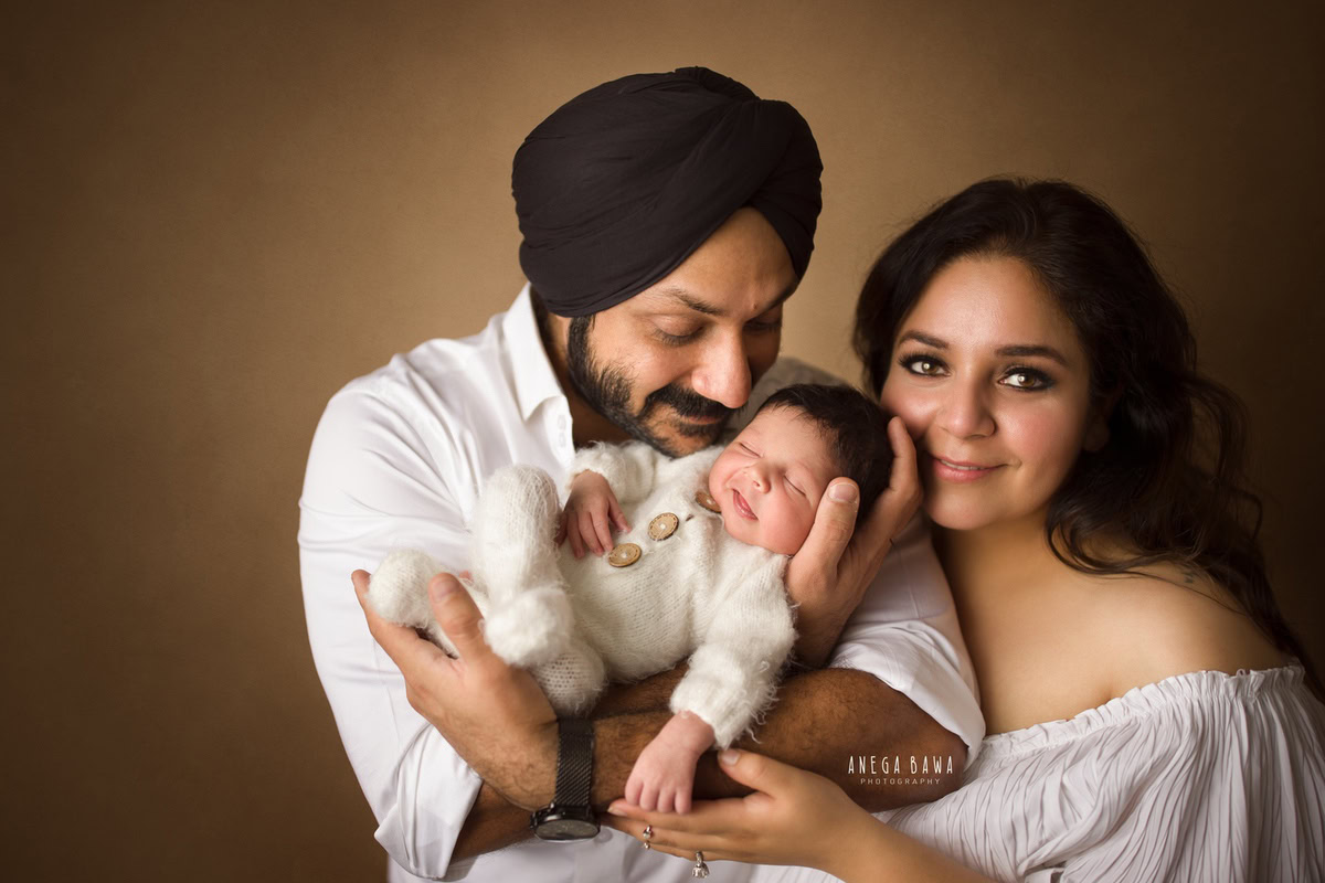 Newborn Photography in Delhi: Family portrait with a brown backdrop captured by Anega Bawa Photography in Gurgaon.