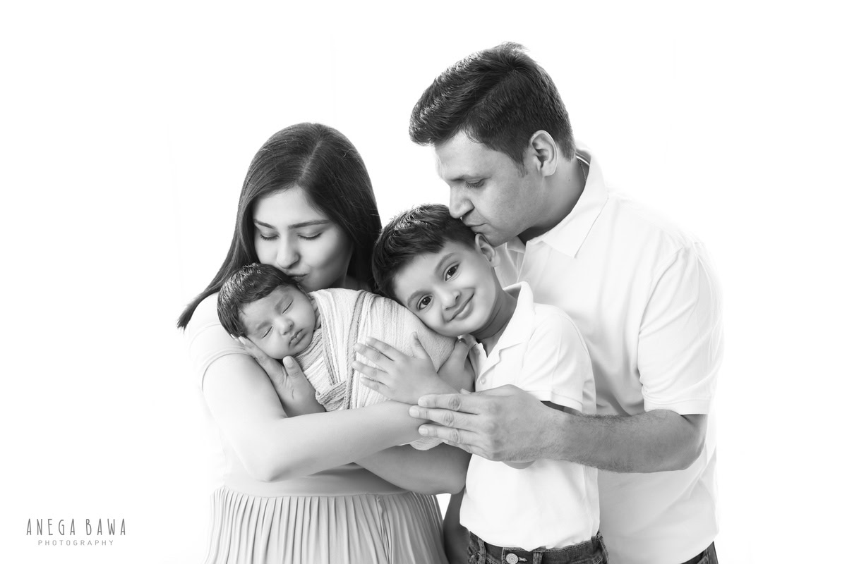 Newborn Photography in Delhi: Family posing against a white backdrop, photographed by Anega Bawa in Gurgaon.