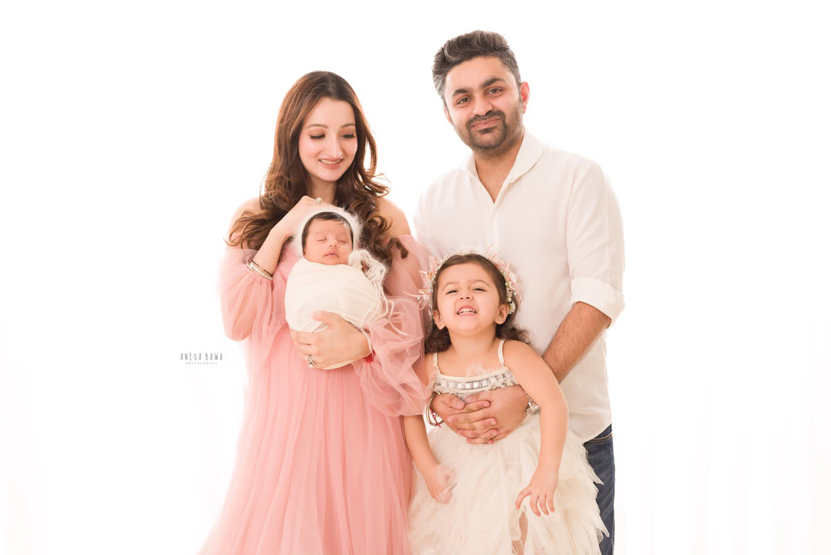 Newborn Photography in Delhi: Family in a white wrap against a white backdrop. Photographer: Anega Bawa, Gurgaon.