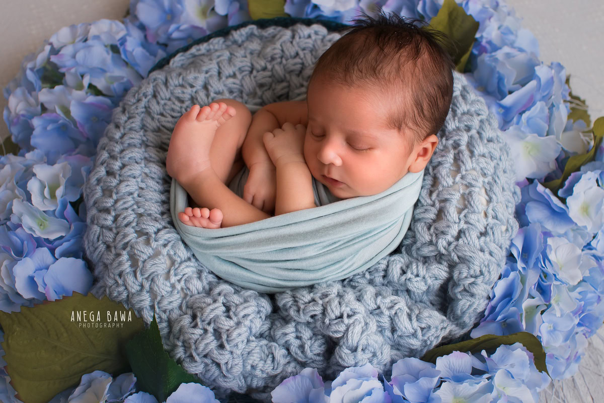 Newborn Photography in Delhi: Floral Blue Basket, Blue Wrap, Grey Backdrop. Photographer: Anega Bawa Photoshoot, Gurgaon Noida.