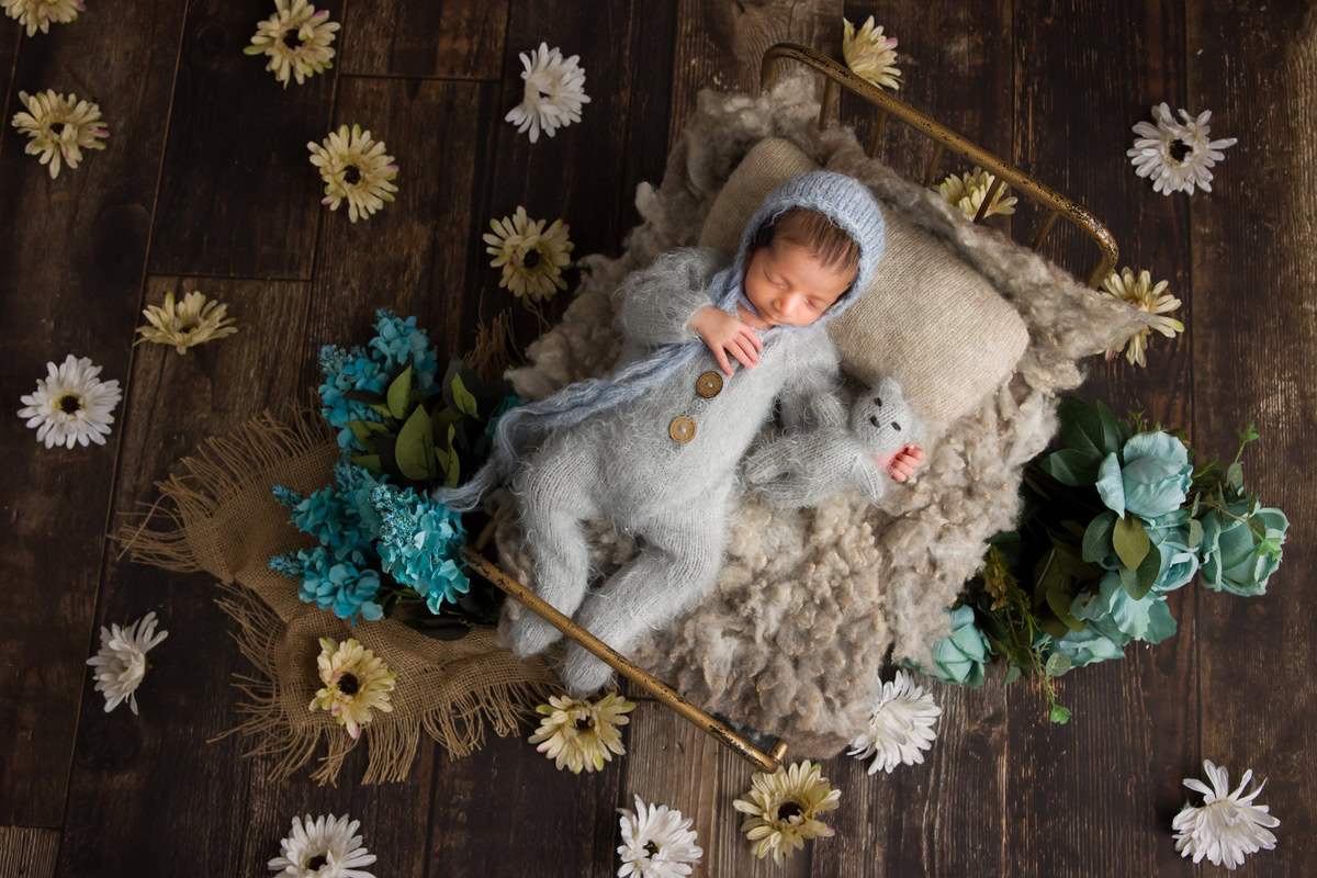 Newborn Photography in Delhi: Grey Baby Suit, Yellow and White Flowers on Floor, Grey Soft Toy, Wooden Backdrop, by Anega Bawa Photographer, Gurgaon Noida.