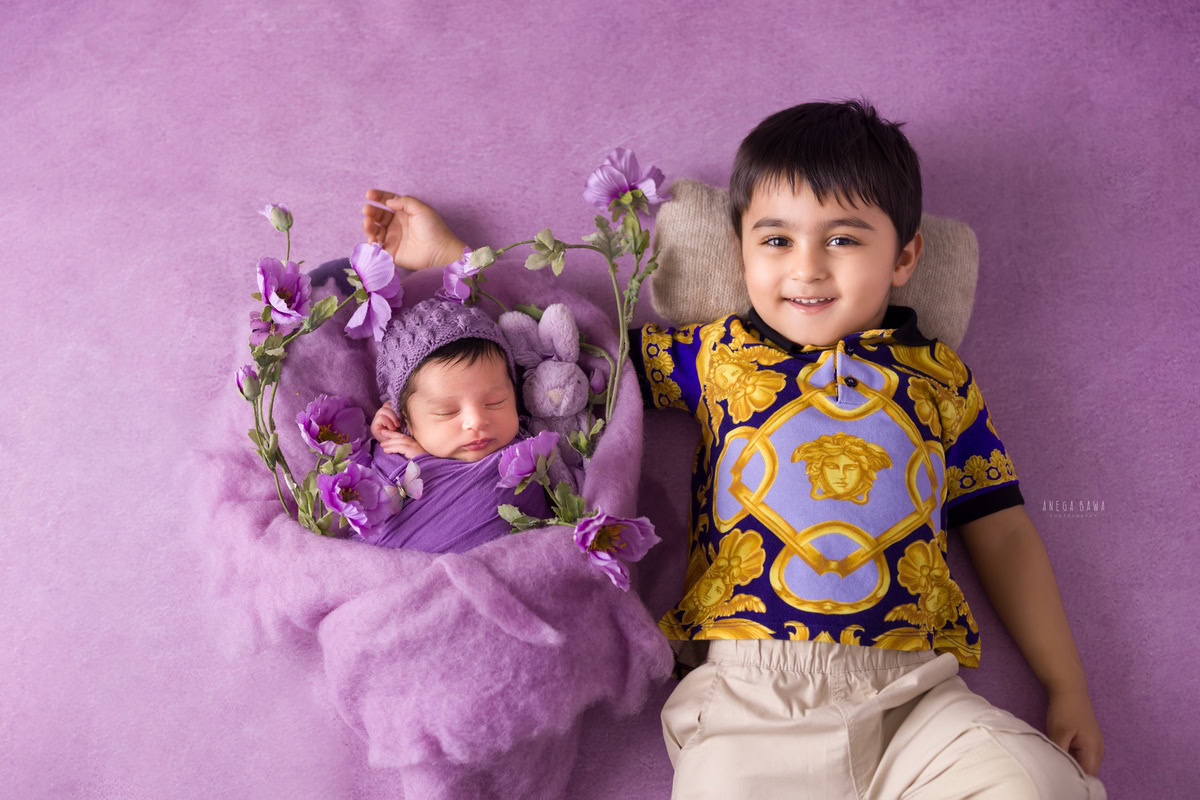 Newborn Photography in Delhi: Lavender Wrap, Lavender Backdrop, Sibling with Flowers. Photographer: Anega Bawa Photoshoot, Gurgaon Noida.