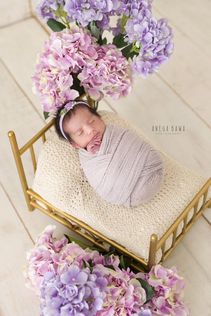 Newborn Photography in Delhi: Mauve Wrap, Cute Golden Cot, Beige Backdrop, Cute Headband. Photographer: Anega Bawa Photoshoot, Gurgaon Noida.