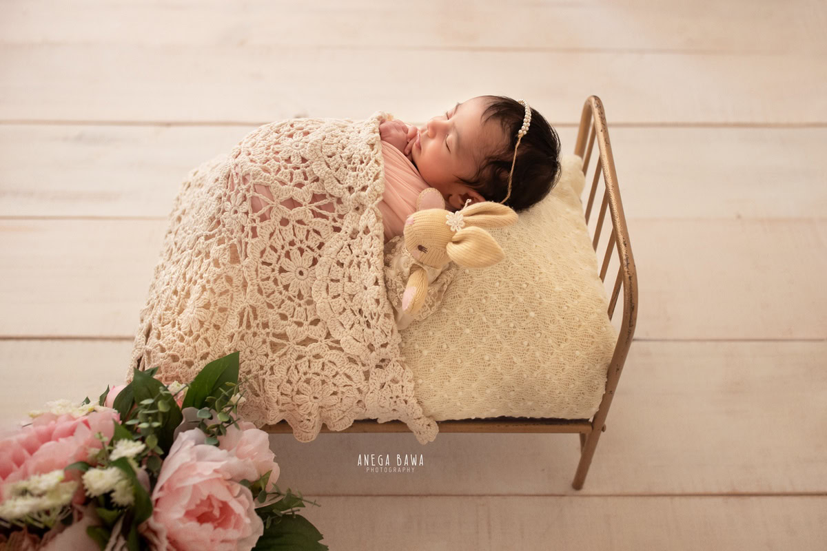 Newborn Photography in Delhi: Sleeping Pose with Soft Toy, Beige Backdrop, Pearl Headstring. Photographer: Anega Bawa, Gurgaon Noida.
