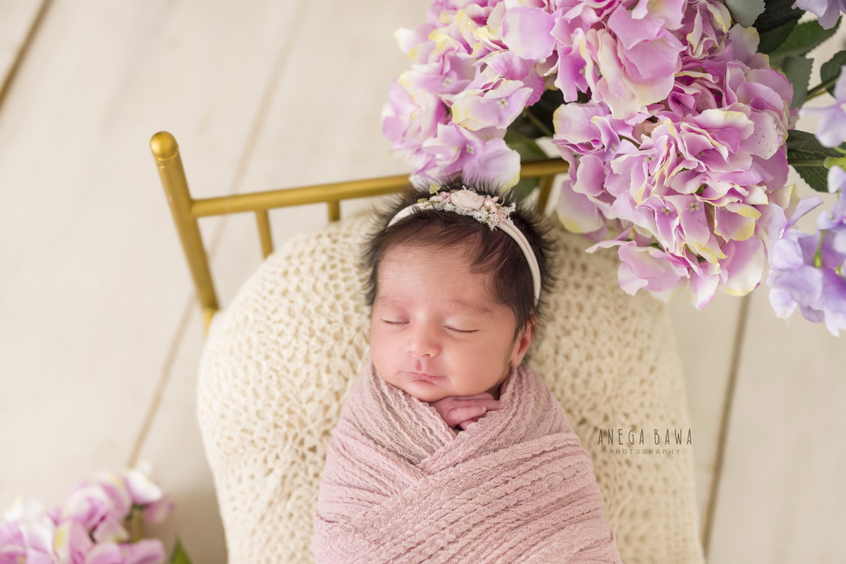Newborn Photography in Delhi: Pink Wrap with Pink Flowers, Beige Backdrop. Photographer: Anega Bawa, Gurgaon Noida.