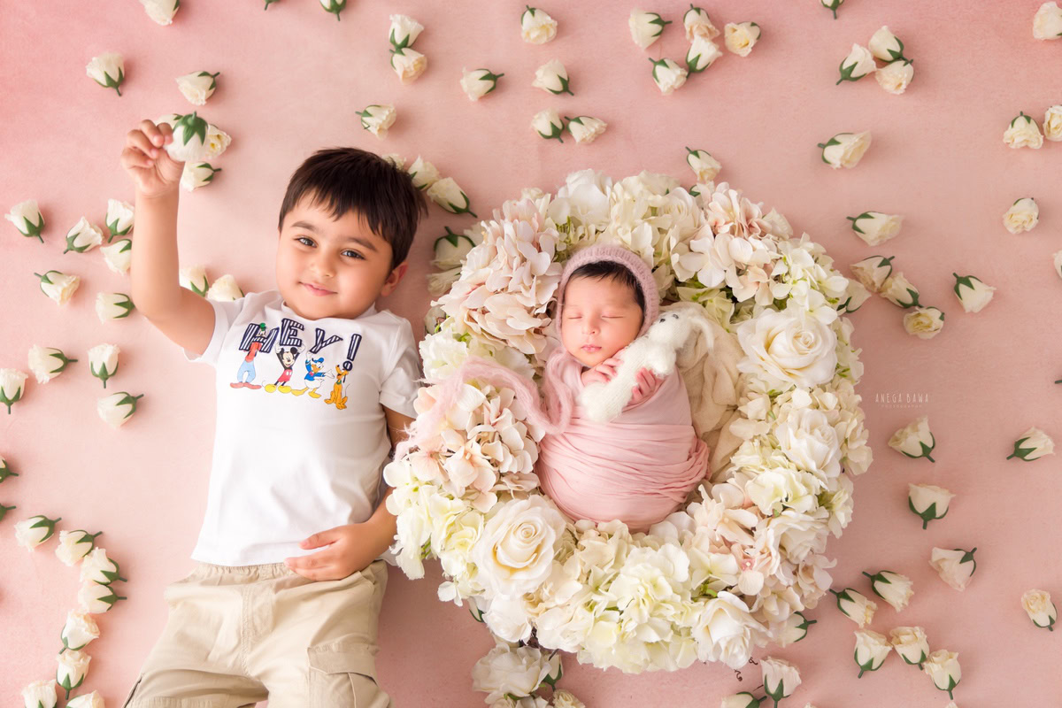 newborn-photography-delhi-pink-wrap-sibling-floral-basket-soft-toy-pink-backdrop-anega-bawa-photographer-gurgaon-noida