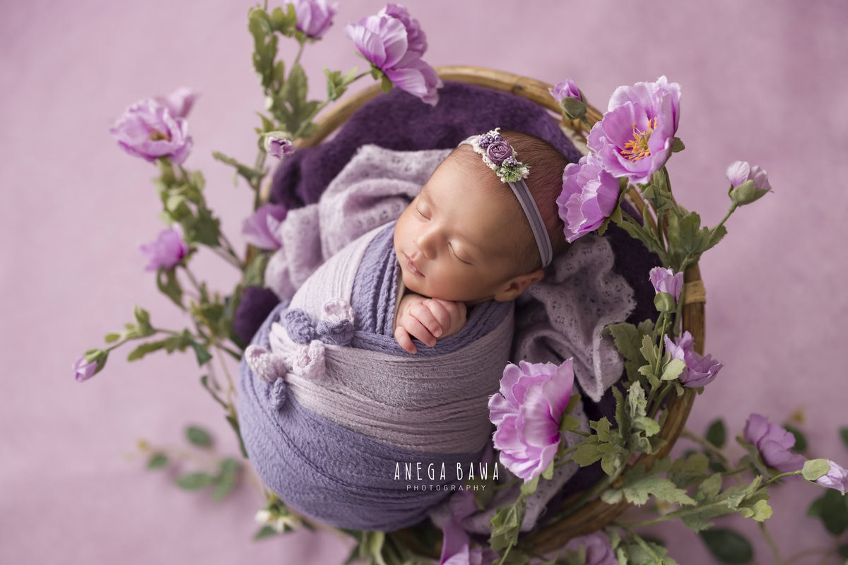 Newborn Photography in Delhi: Purple Mauve Wrap with Leafy Lavender Flowers in Wooden Basket. Photographer: Anega Bawa, Gurgaon Noida.