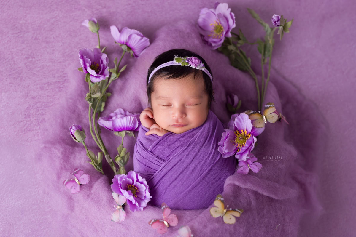 Newborn Photography in Delhi: Purple Wrap with Lavender Backdrop and Flowers. Photographer: Anega Bawa, Gurgaon Noida.
