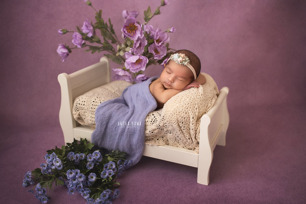 Newborn Photography in Delhi: Purple Wrap with Lavender Backdrop and Lavender Blue Flowers. Photographer: Anega Bawa, Gurgaon Noida.