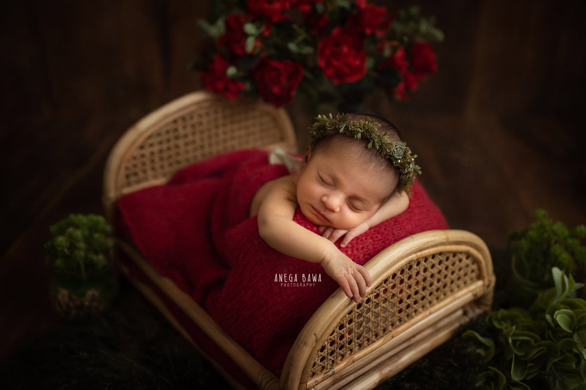 Newborn Photography in Delhi: Red Wrap with Red Flowers, Black Backdrop, by Anega Bawa Photographer, Gurgaon Noida.