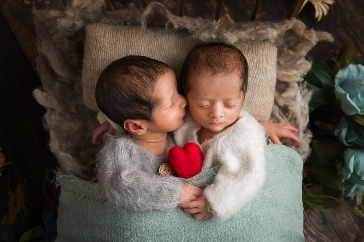 Newborn Photography in Delhi: Twins in Kissing Pose with Red Heart Soft Toy and Blue Blanket, by Anega Bawa Photographer, Gurgaon Noida.