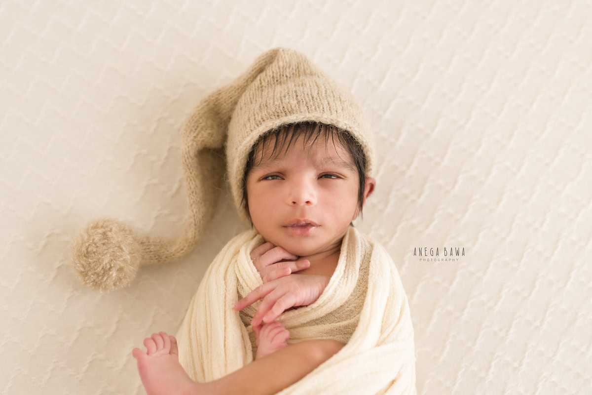 Newborn Photography in Delhi: White Wrap with Brown Cap, White Backdrop. Photographer: Anega Bawa, Gurgaon Noida.