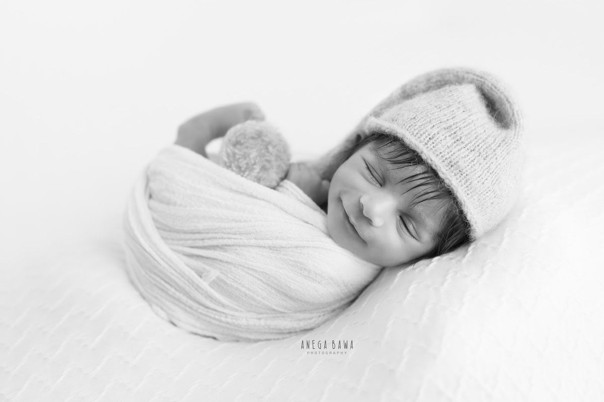 Newborn Photography in Delhi: White Wrap with Cap in Smiling Pose, by Anega Bawa Photographer, Gurgaon Noida.