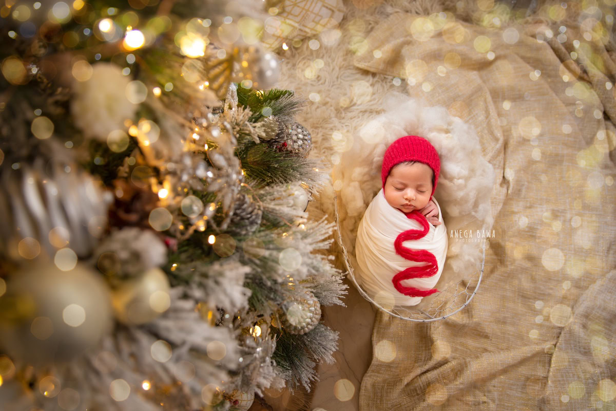 Newborn Photography in Delhi: White Wrap with Red Cap, Xmas Tree, Bubble Backdrop. Photographer: Anega Bawa, Gurgaon Noida.