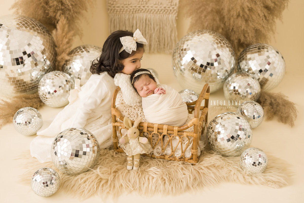 Newborn Photography in Delhi: White Wrap with Sibling Kissing Pose, Discoball, Pampas, by Anega Bawa Photographer, Gurgaon Noida.