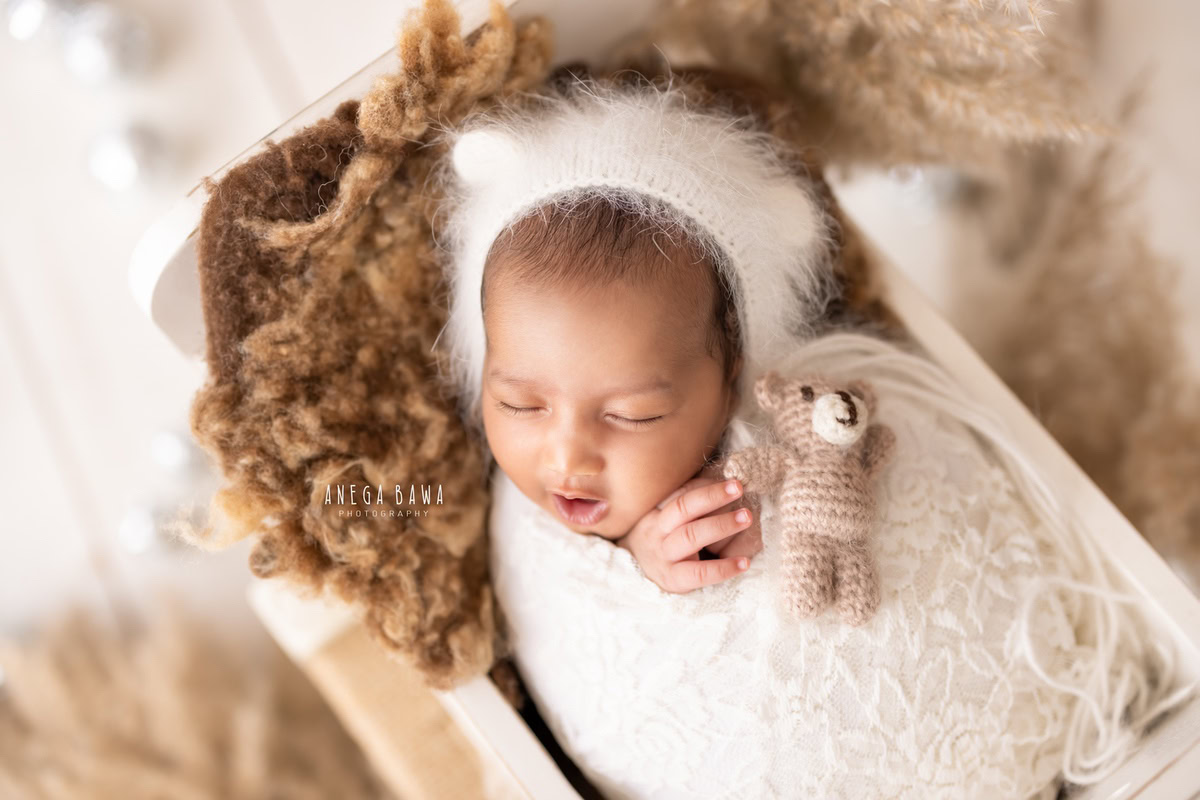 Newborn Photography in Delhi: White Wrap with Soft Toy, Capturing a Cute Yawning Pose. Photographer: Anega Bawa, Gurgaon Noida.