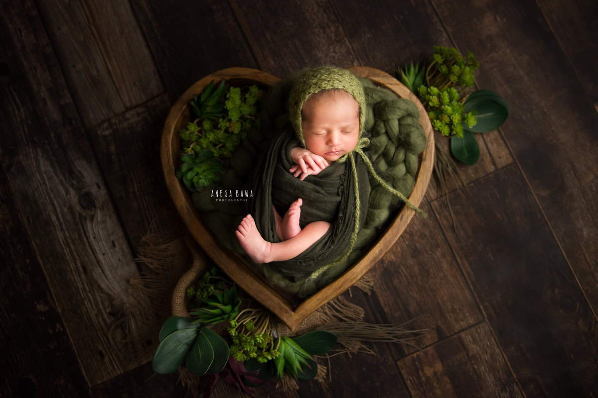 Newborn Photography at Home in Delhi: Green Wrap with Heart-shaped Basket and Green Cap. Photographer: Anega Bawa, Gurgaon Noida.