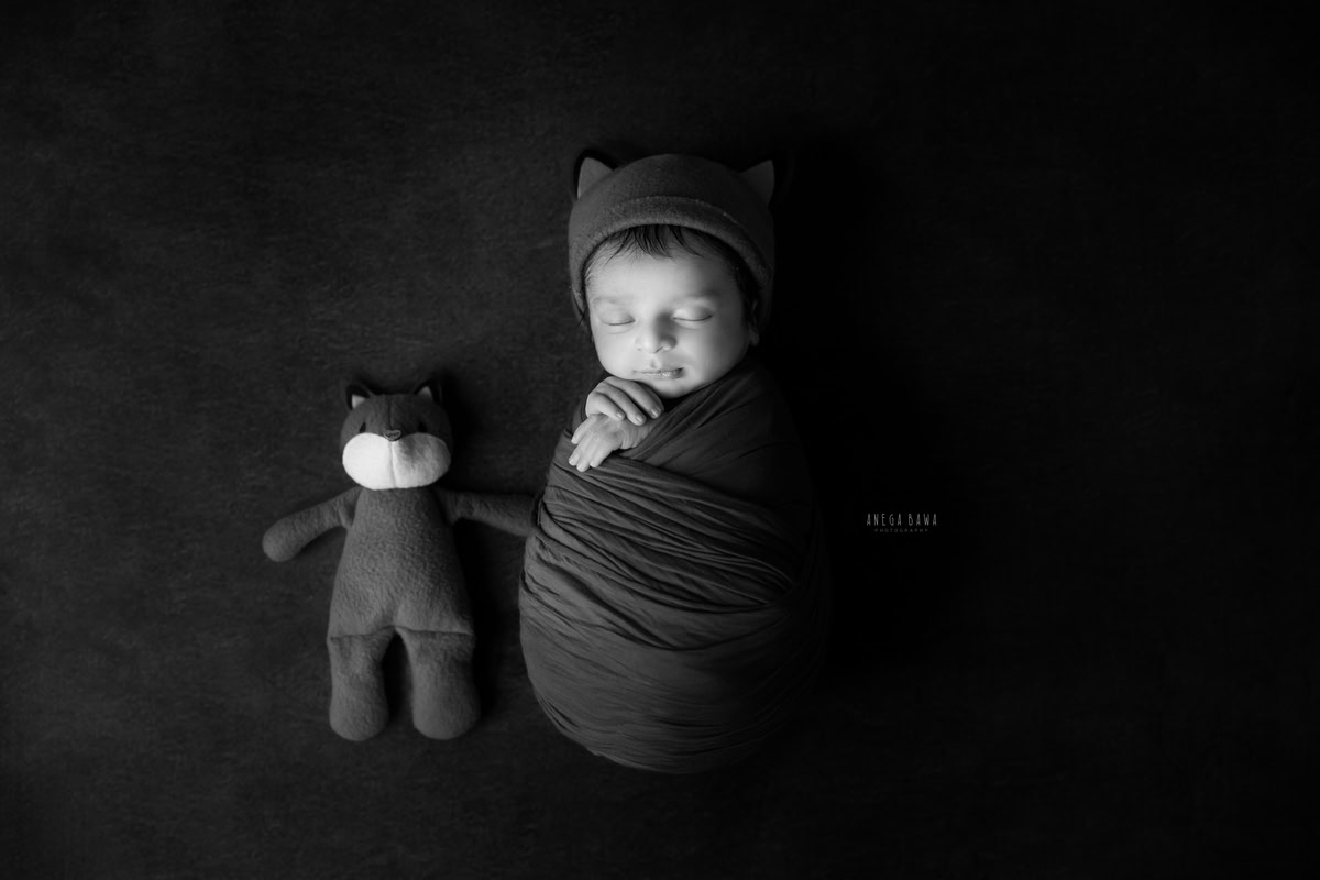 Newborn Photography at Home in Delhi: Red Wrap with Soft Toy, Black and White Theme. Photographer: Anega Bawa, Gurgaon Noida.