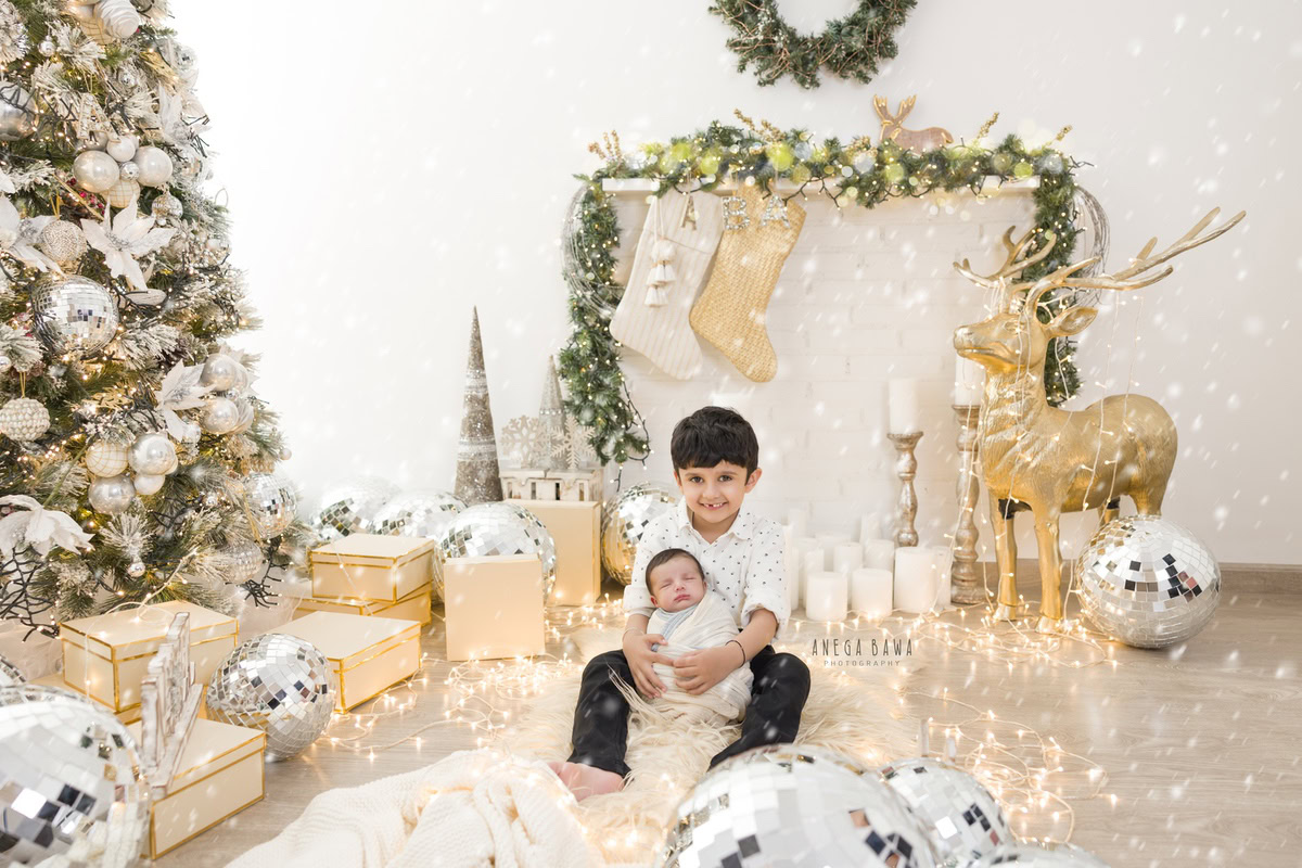 Newborn Photoshoot in Delhi: Blue and White Wrap with Sibling, Xmas Tree, Candles, Discoball, Golden Lights. Photographer: Anega Bawa Photography, Gurgaon Noida.