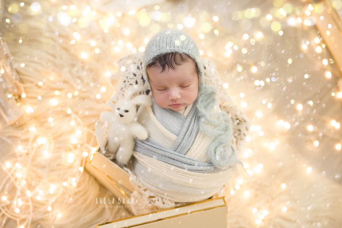 Newborn Photoshoot in Delhi: Blue and White Wrap with a Stuff Toy on a Beige Rug, Illuminated with Lights. Photographer: Anega Bawa, Gurgaon Noida.