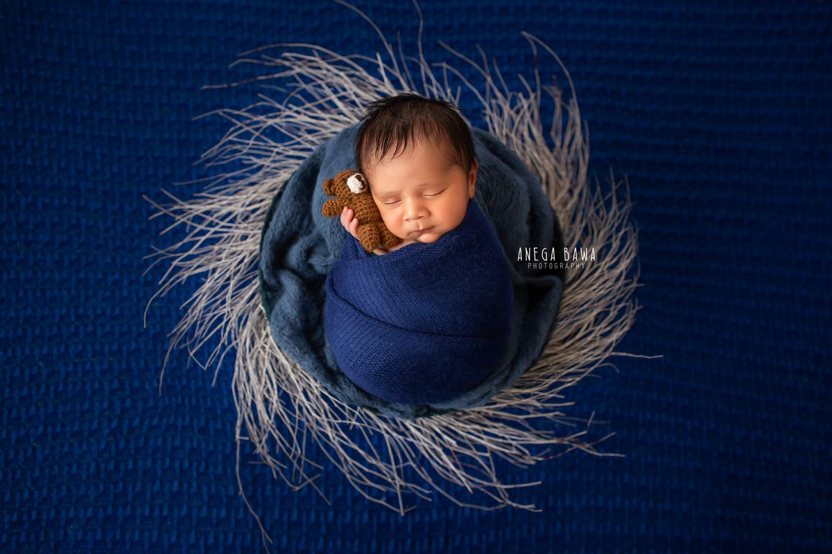 Newborn Photoshoot in Delhi: Blue Wrap with Blue Backdrop, Grey Feather Accent. Photographer: Anega Bawa Photography, Gurgaon Noida.