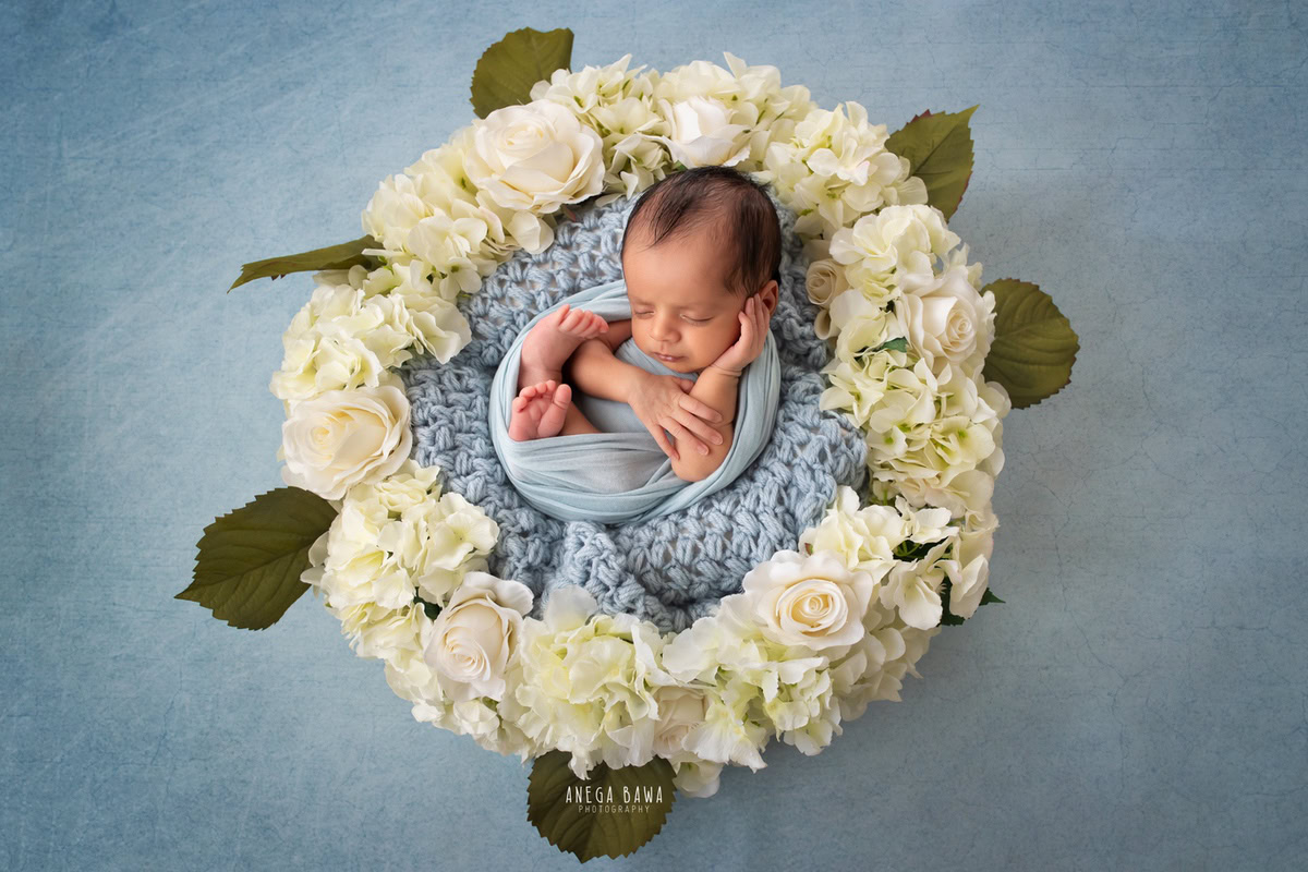 Newborn Photoshoot in Delhi: Blue Wrap with Floral Basket on Blue Backdrop. Photographer: Anega Bawa Photography, Gurgaon Noida.