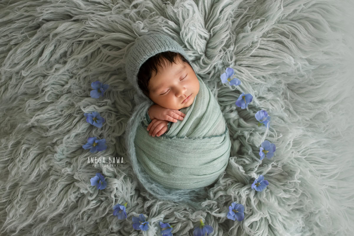Newborn Photoshoot in Delhi: Blue Wrap, Sleeping Pose on Grey Rug, with Grey Backdrop. Photographer: Anega Bawa Photography, Gurgaon Noida.