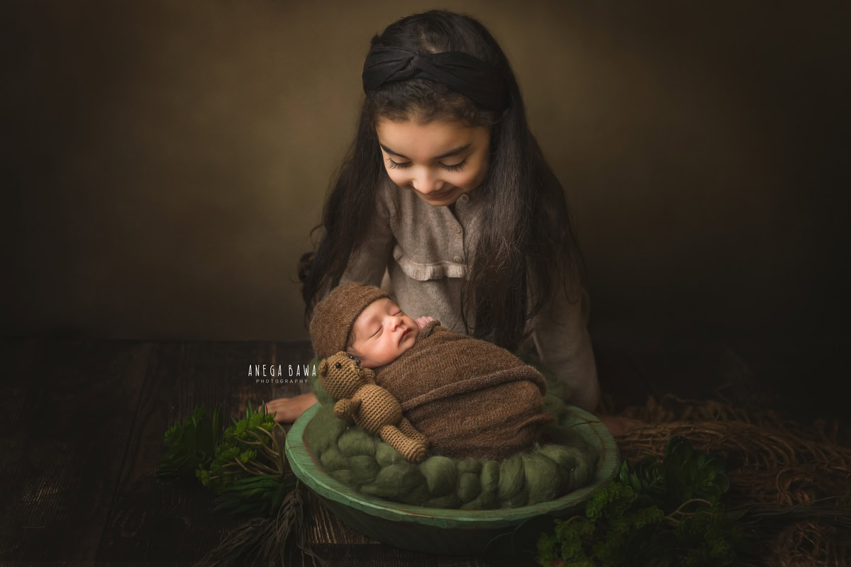 Newborn Photoshoot in Delhi: Green Basket, Brown Wrap, Sibling, Brown Backdrop. Photographer: Anega Bawa Photography, Gurgaon Noida.