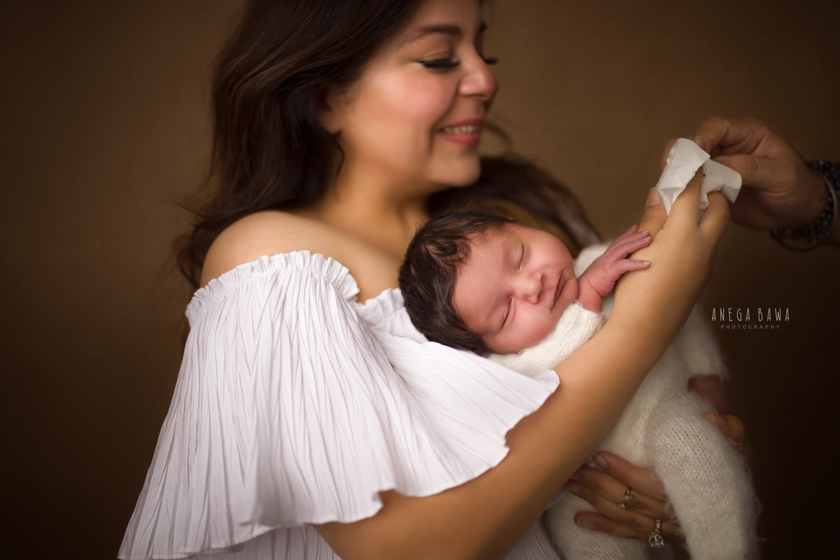 Newborn Photoshoot in Delhi: Mom with her newborn in a white babysuit. Photographer: Anega Bawa Photography, Gurgaon.
