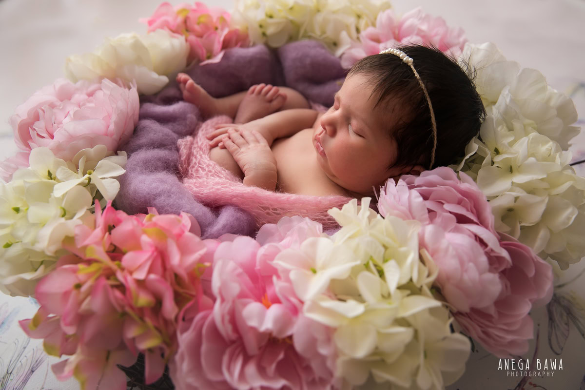 Newborn Photoshoot in Delhi: Pink Wrap, Floral Basket, White Backdrop. Photographer: Anega Bawa Photography, Gurgaon Noida.