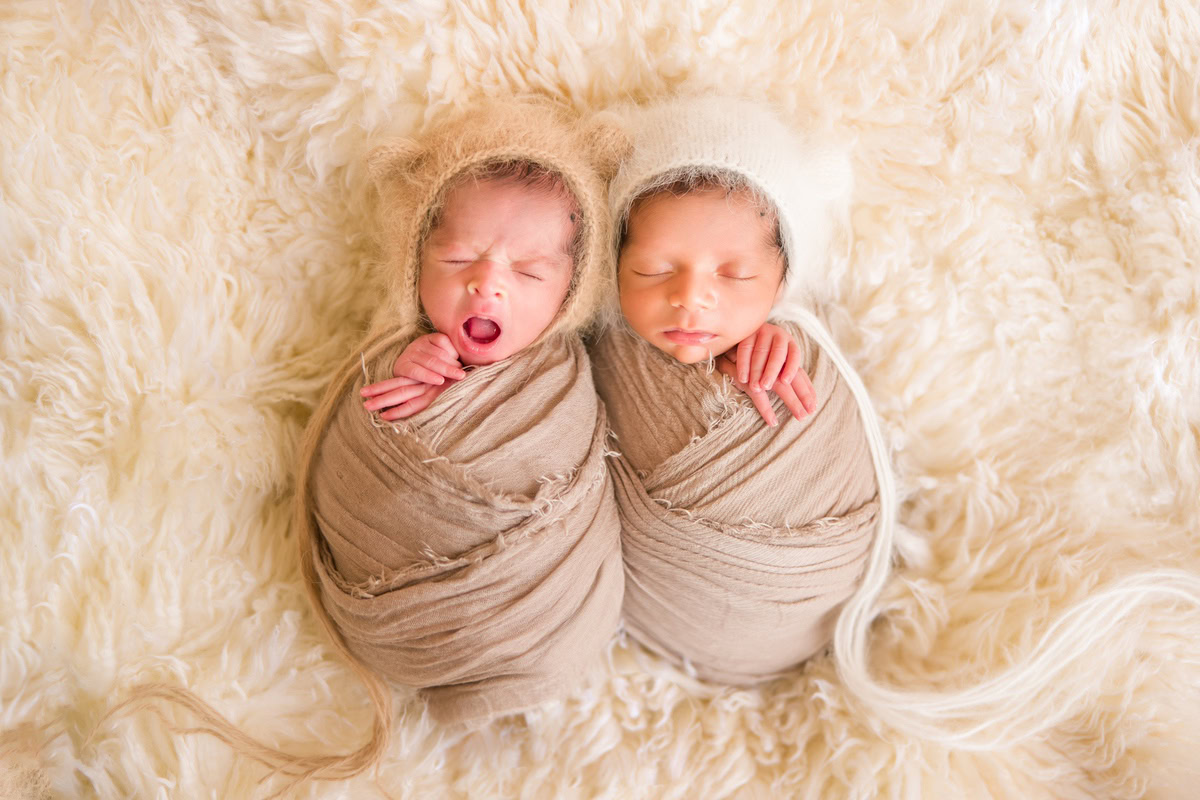 Newborn Photoshoot in Delhi: Siblings in Brown Wrap, Beige Rug, Beige Backdrop. Photographer: Anega Bawa Photography, Gurgaon Noida.