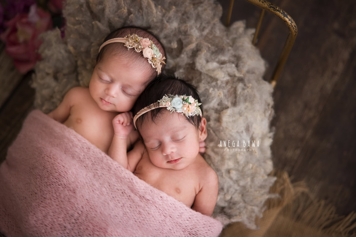 Newborn Photoshoot in Delhi: Twins with Pink Blanket and Cute Headbands on Grey Rug. Photographer: Anega Bawa Photography, Gurgaon Noida.