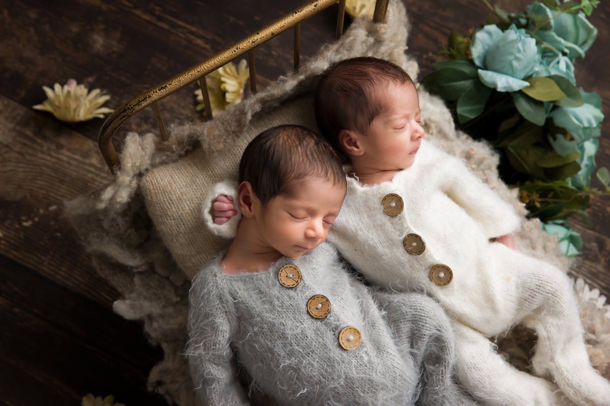 Newborn Photoshoot in Delhi: Twins in Wooden Basket with Wooden Backdrop, dressed in White Baby Suits and Grey Baby Suits. Photographer: Anega Bawa Photography, Gurgaon Noida.