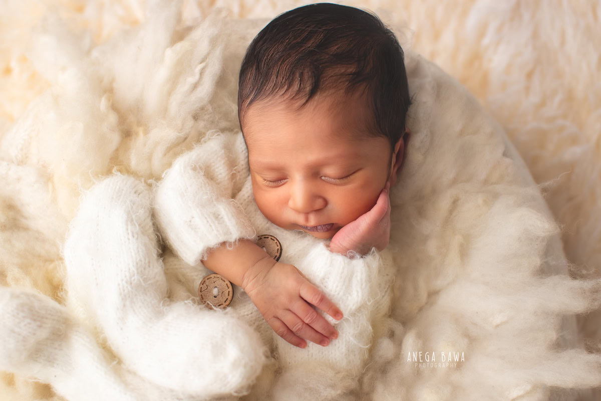 Newborn Photoshoot in Delhi: White Baby Suit in a Cute Sleeping Pose. Photographer: Anega Bawa Photography, Gurgaon Noida.