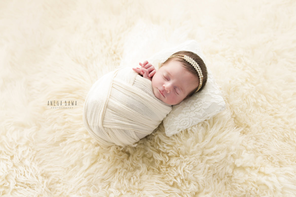 Newborn Photoshoot in Delhi: White Wrap, Beige Backdrop, Pearl Headstring. Photographer: Anega Bawa, Gurgaon Noida.