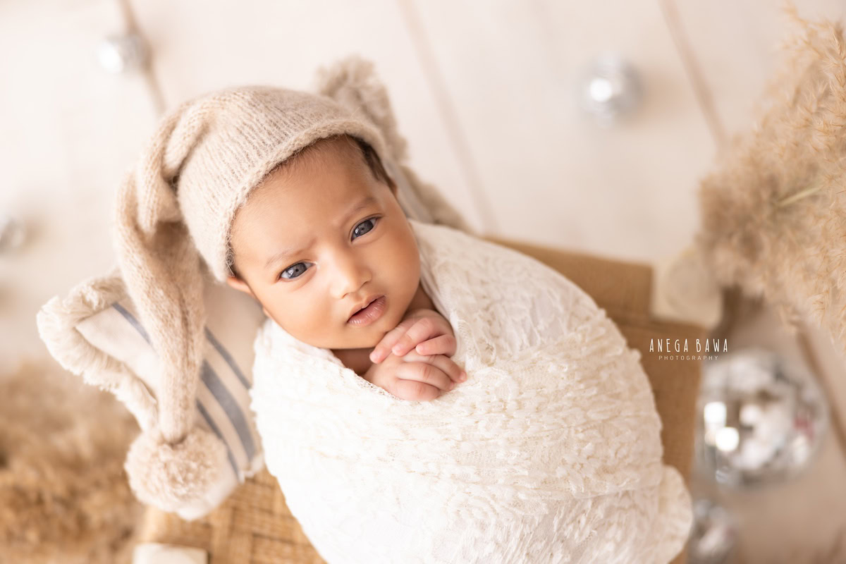 Newborn Photoshoot in Delhi: White Wrap, Brown Cap, Silver Balls. Photographer: Anega Bawa, Gurgaon Noida.