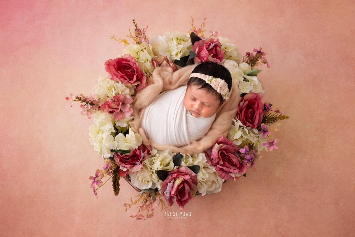 Newborn Photoshoot in Delhi: White Wrap with Floral Basket, Peach Backdrop. Photographer: Anega Bawa, Gurgaon Noida.